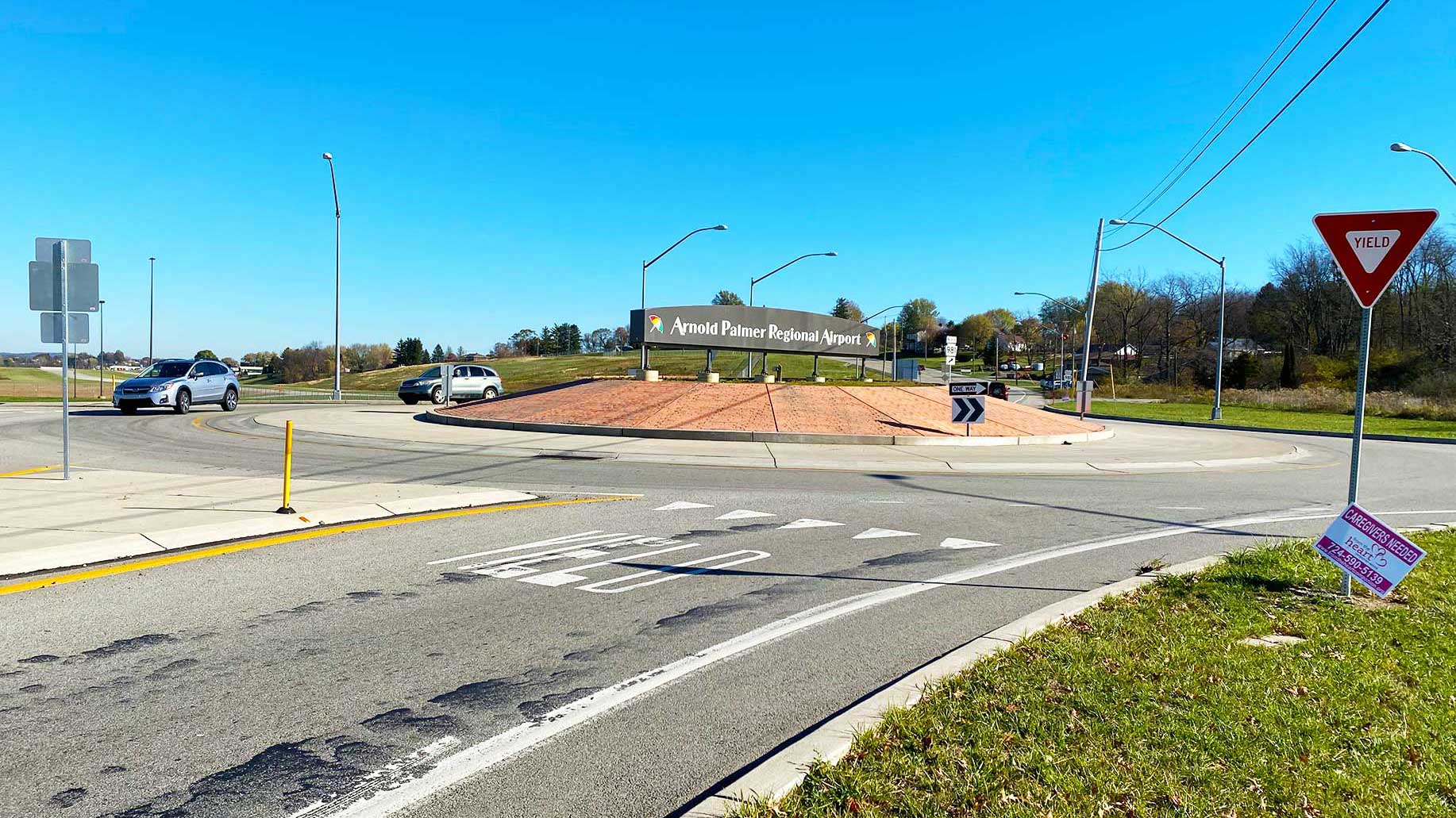 Cars driving a roundabout with a sign for the airport in center